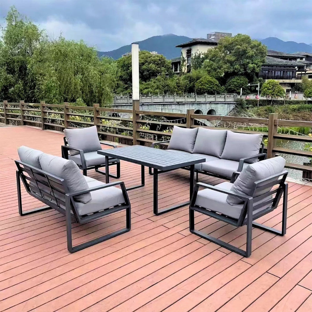 Outdoor patio set with table and chairs on a wooden deck with a scenic background.