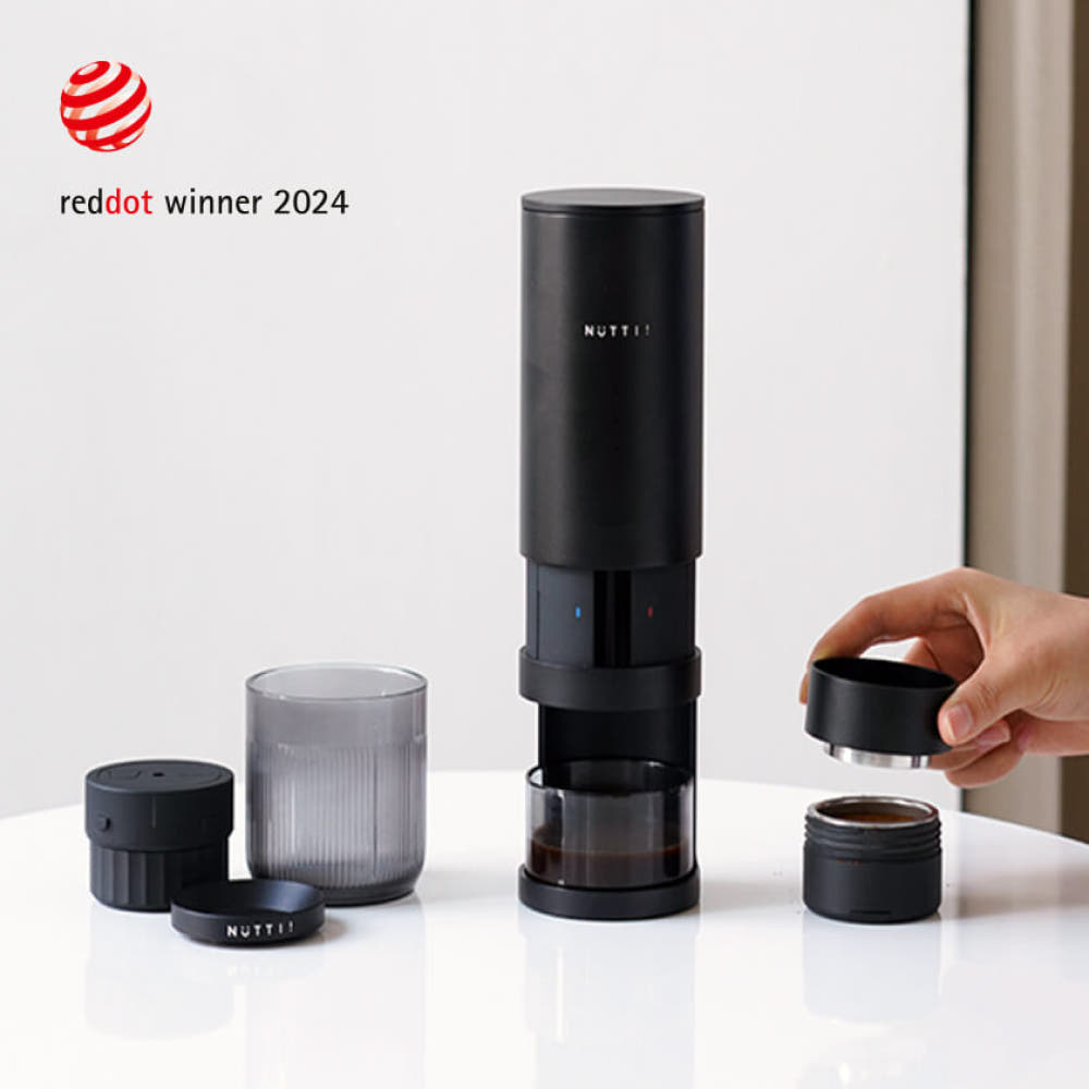 Black coffee maker with components on a white surface, featuring the Red Dot Award logo.