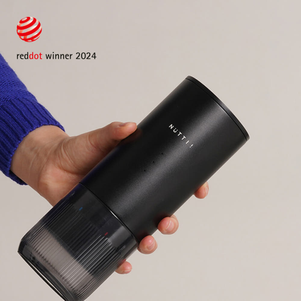 Black cylindrical device with 'NUTLI' branding held by a person, against a neutral background with Red Dot Award logo.